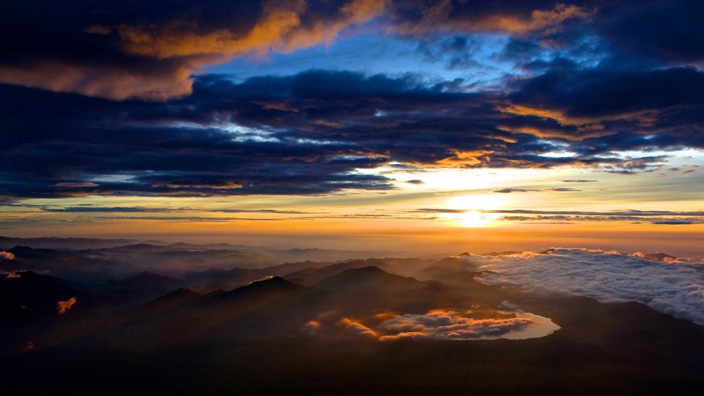 aerial photo of mountain under blue and white cloudy sky during daytime