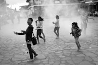 Children playing joyfully in a village square surrounded by rustic houses.