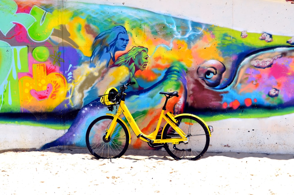 green bicycle park beside wall with human painting during daytime
