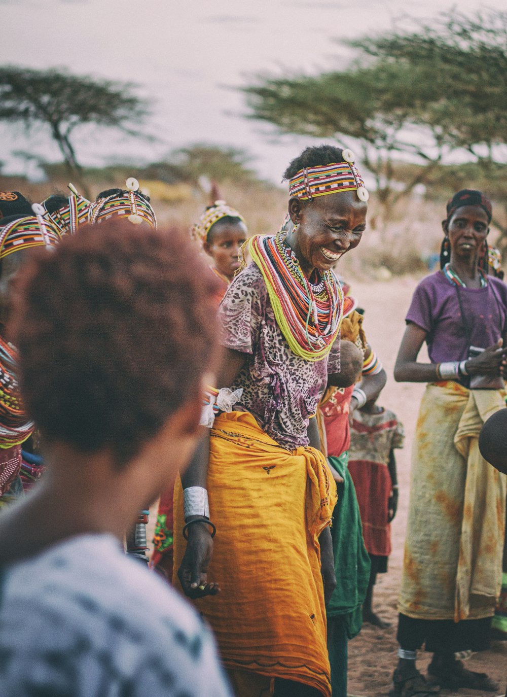 Mujer sonriente bailando alrededor de la gente en la tribu durante el día