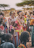 A group of people adorned in colorful traditional attire, featuring intricate beadwork and patterns. The individuals appear engaged in conversation and smiling, with a woman carrying a child on her back. The background includes sparse trees, suggesting a rural setting.