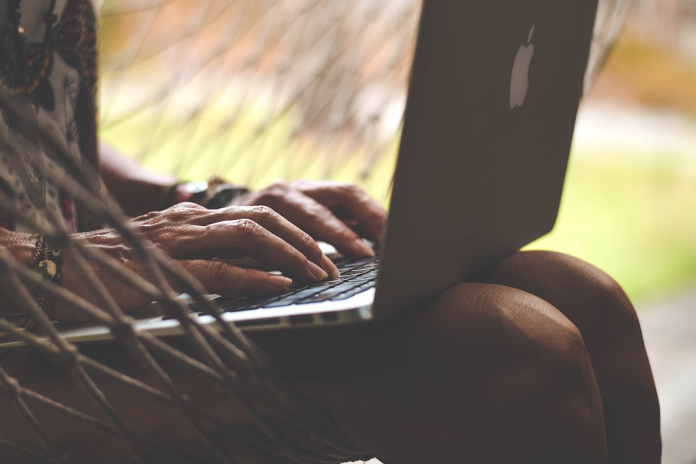 a person sitting in a hammock using a laptop