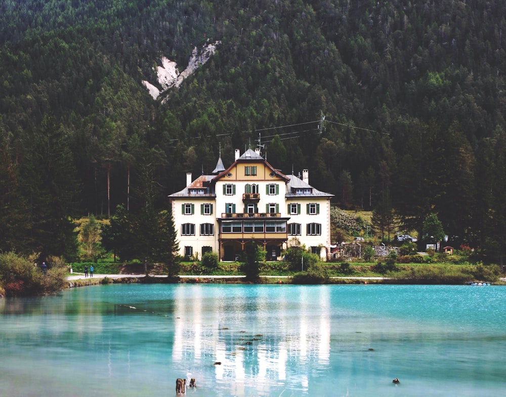 white and brown house near body of water in forest