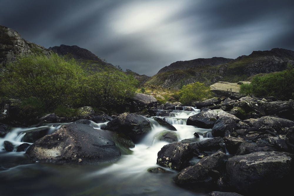 time lapse photo of riverbed and lush grass field during cloudy day