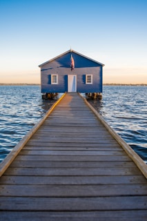 blue and white wooden house on sea under clear blue sky during daytime