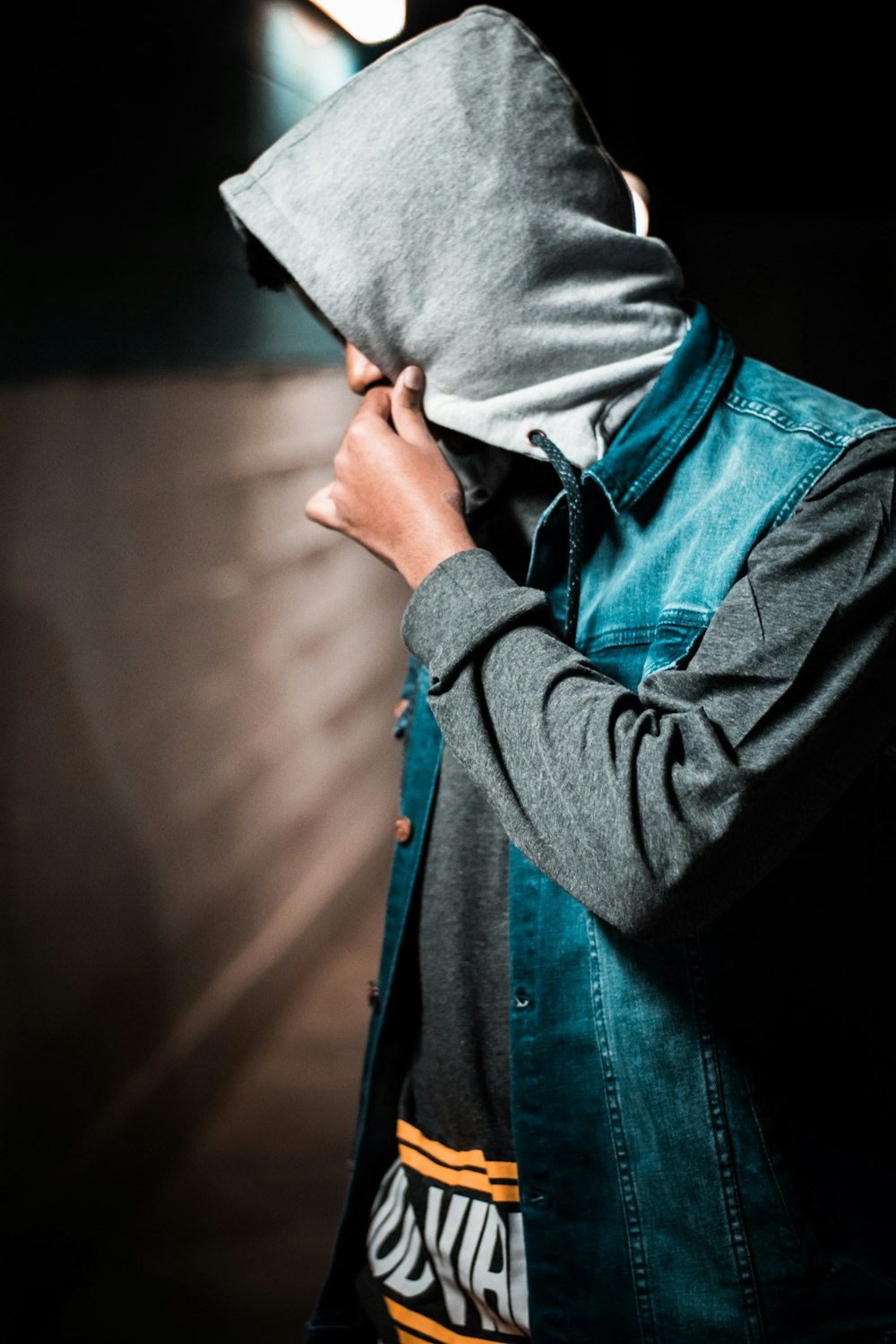 man wearing denim jacket standing near wall