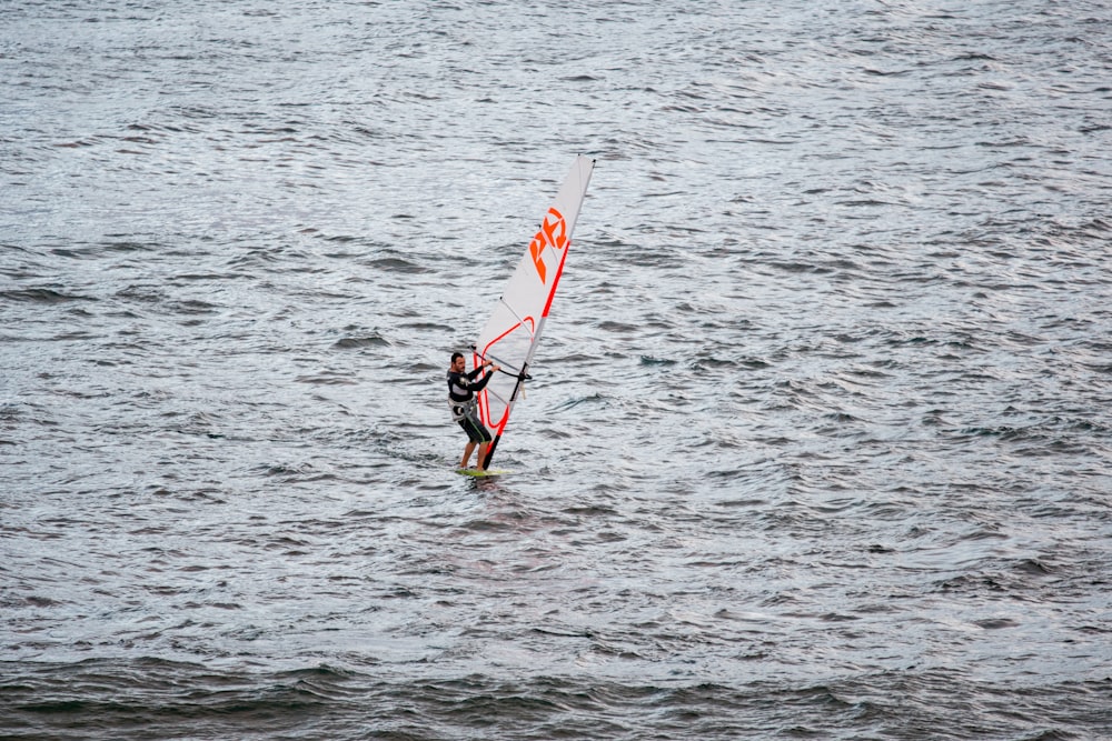 person riding windsurfing on body of water