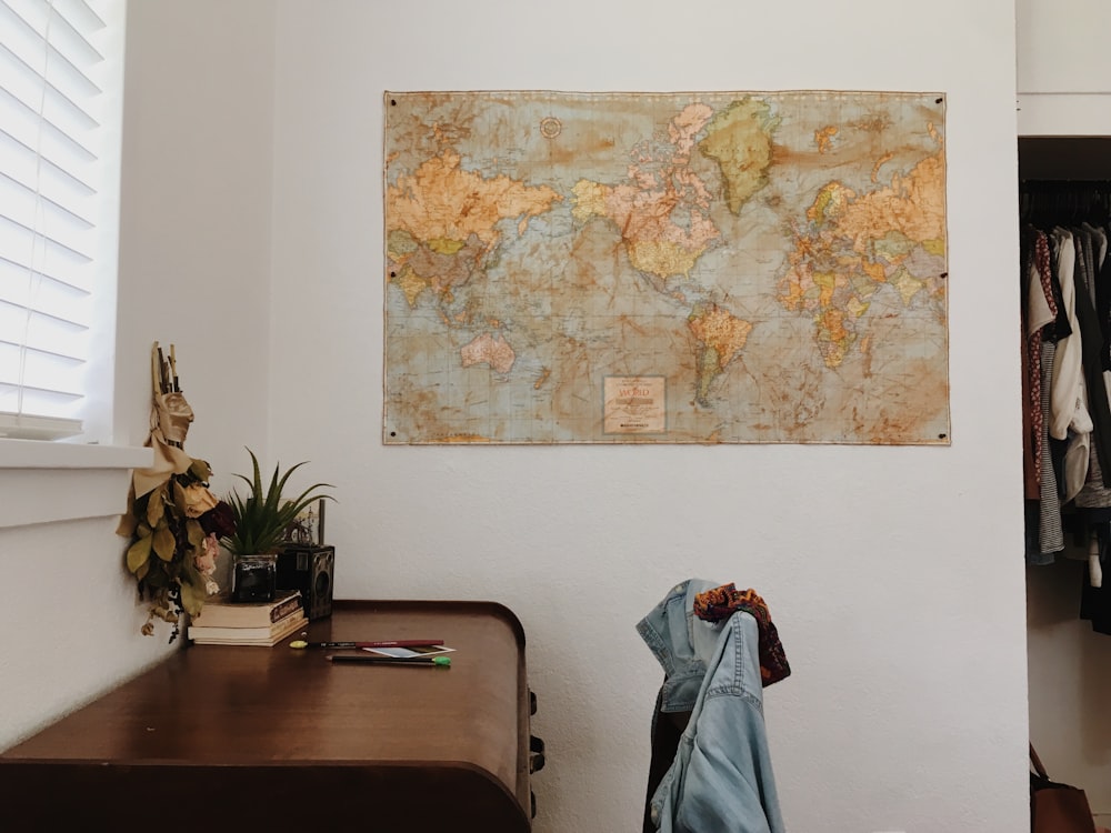 갈색 나무 책상 근처 벽에 세계 지도 놓기