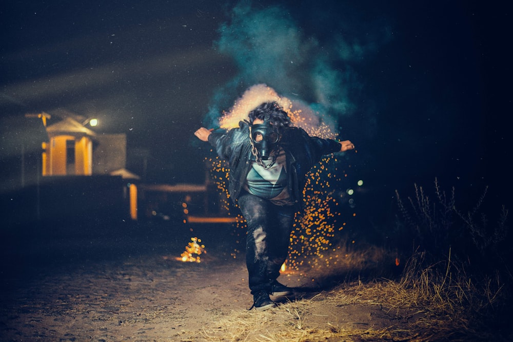 Photo en basse lumière d’un homme portant un bang à masque à gaz sur le point de courir entre l’herbe verte
