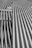 A collection of metallic pipes aligned in parallel and creating a pattern of curves and lines, giving a sense of industrial design.