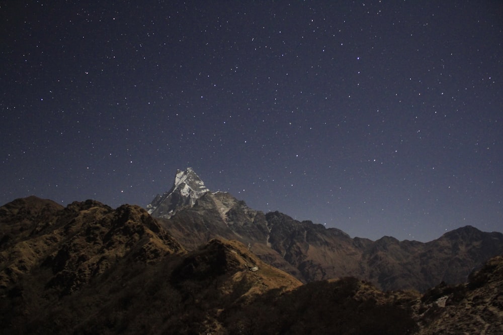 landscape photo of stars above brown mountain ridge