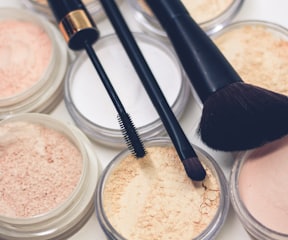 three makeup brushes on top of compact powders