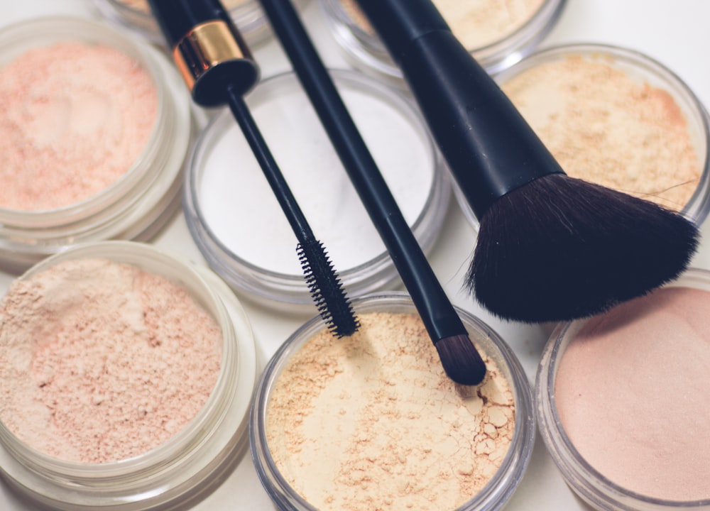 three makeup brushes on top of compact powders