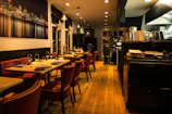 Warm interior shot of Briciola Chicago with olive green walls, dark wood accents, and softly glowing candles on each table