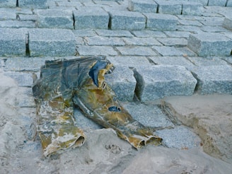 A pair of durable, stylish trousers folded neatly on a stone surface near a flowing stream.