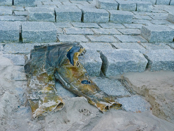 A pair of durable, stylish trousers folded neatly on a stone surface near a flowing stream.