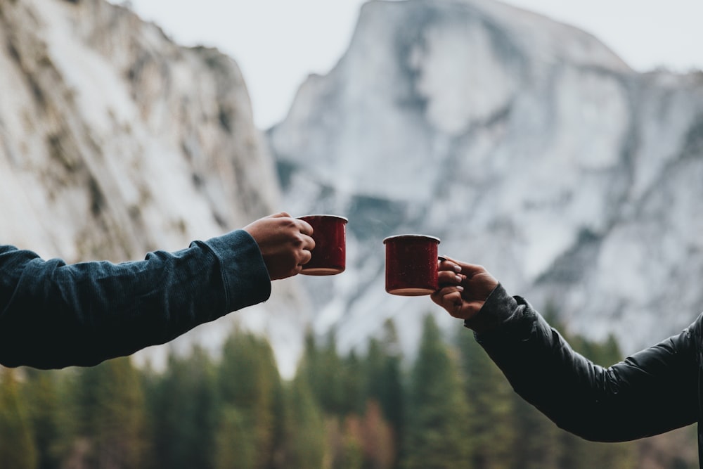 Dos personas sosteniendo tazas rojas