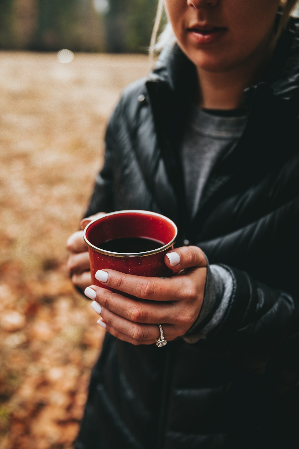 woman holding black liquid-filled red cup selective focus photo