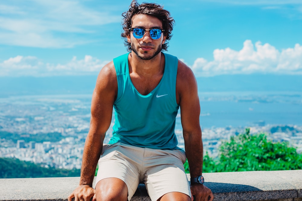 man sitting on grey concrete bench with overview of city on background during daytime