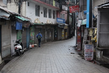 person in blue hoodie walking on street surrounded by buildings