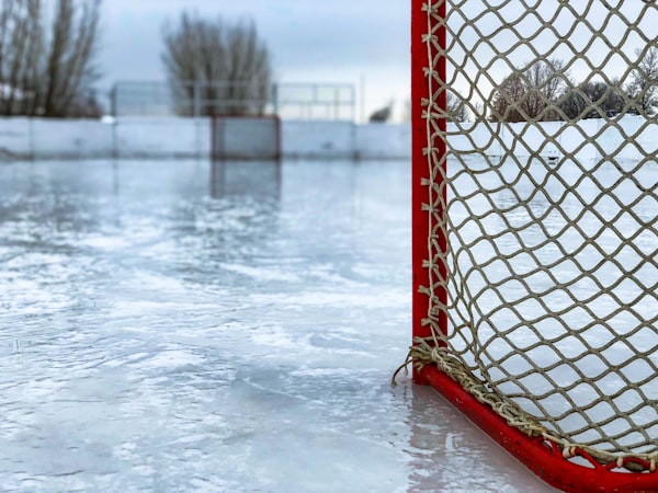 An empty red and white hockey net and goal crease on fresh white ice