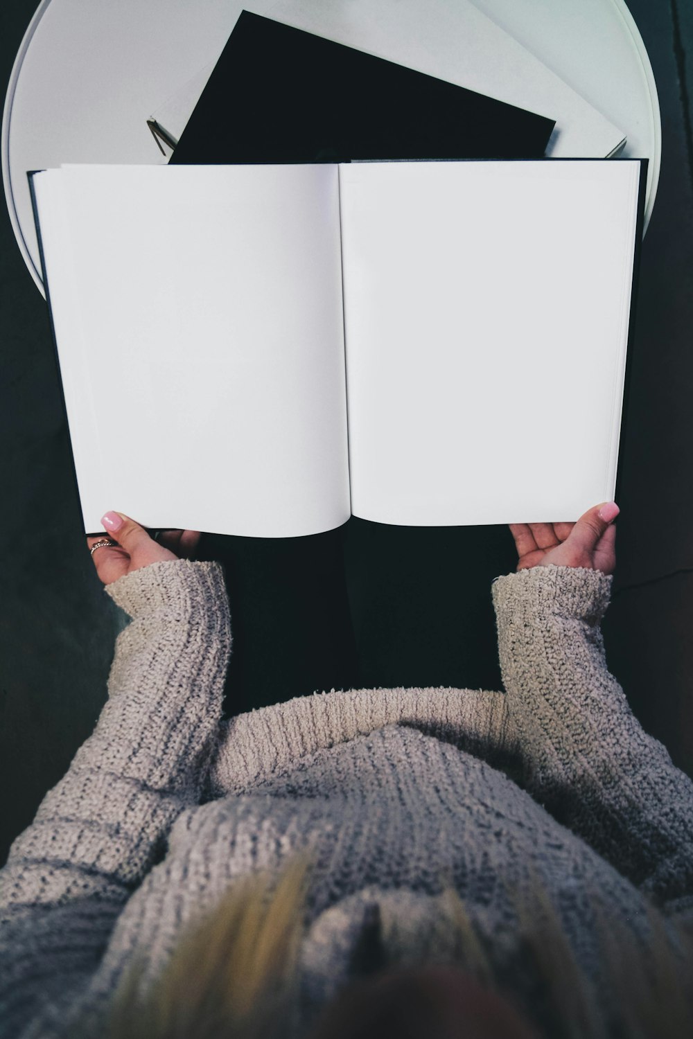 femme portant un pull ouvrant un livre vierge