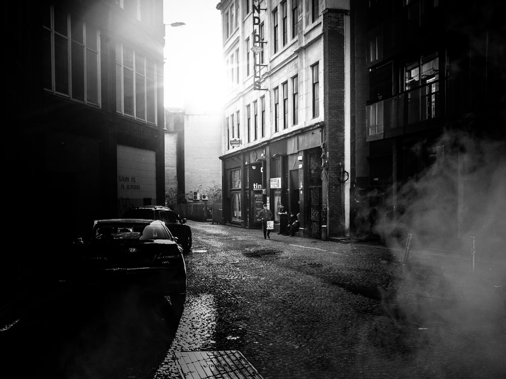 grayscale photo of road between buildings