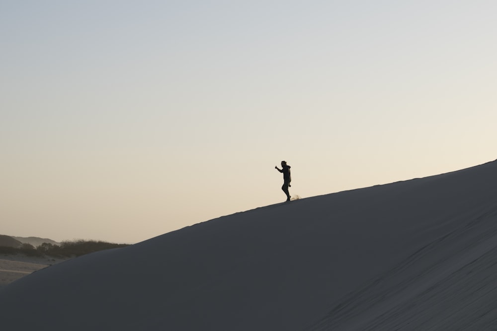 person standing on sand under white sky during daytime