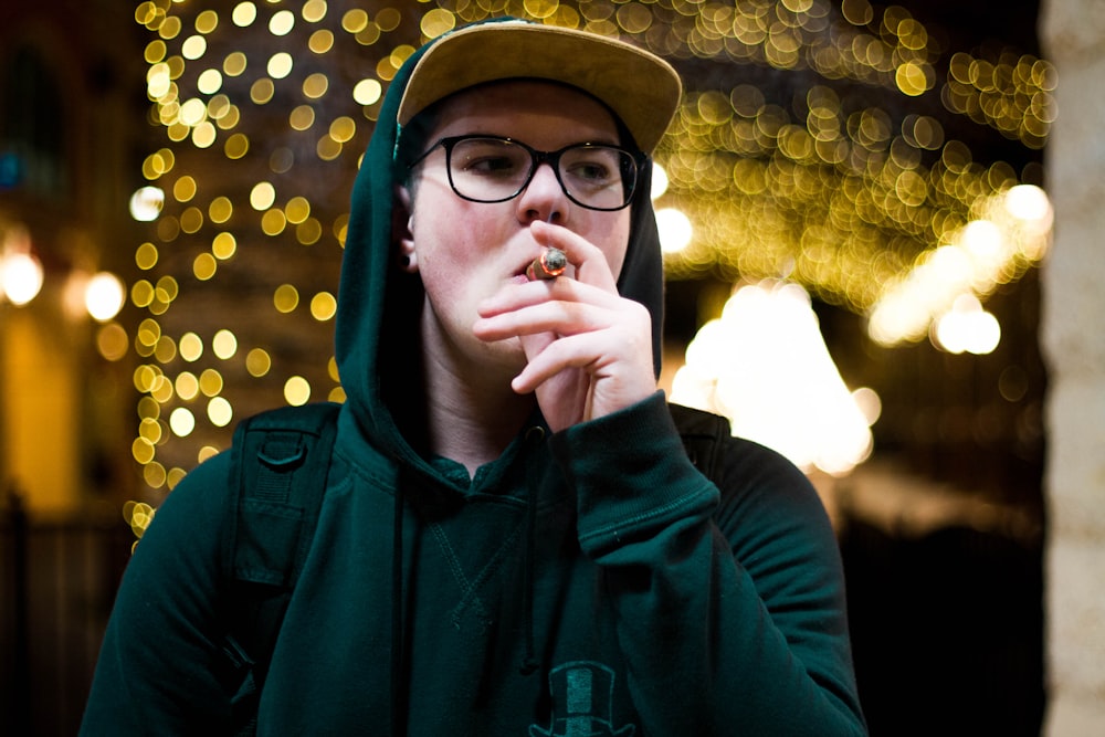 smoking man wearing green pullover hoodie with bokeh background