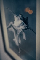 A dramatic black-and-white photo with a subtle purple tint of a dancer mid-leap.
