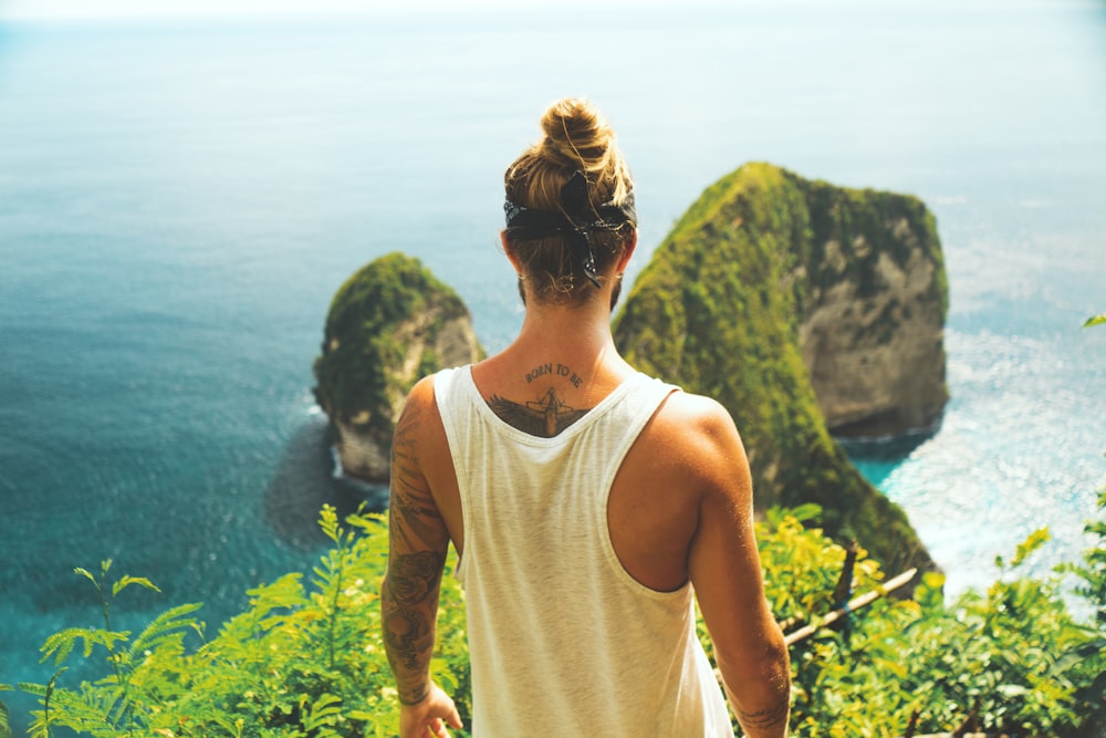 man in white tank top facing near the cliff