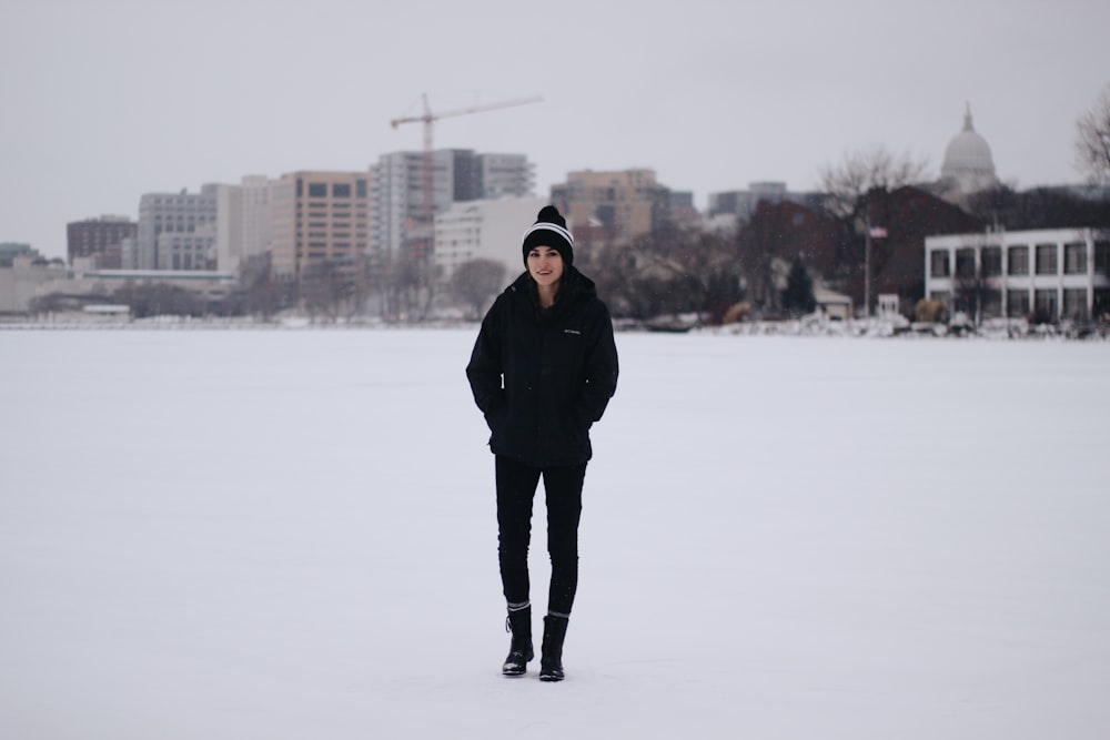 woman walking on field with snow and bulidings