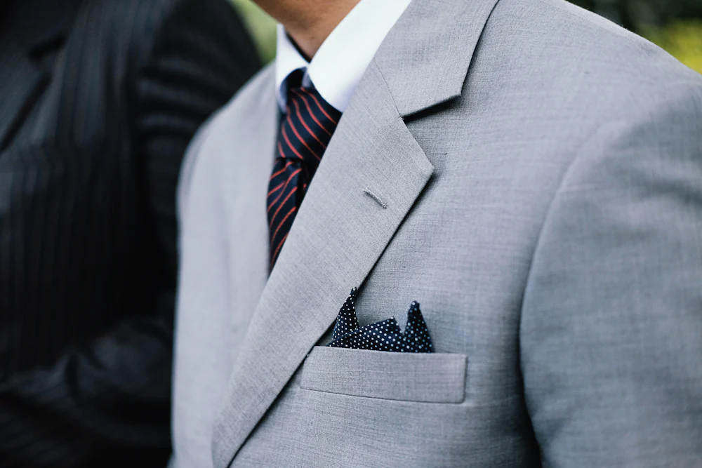 A grey notch lapel suit jacket, worn, photographed close.