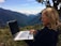 A happy customer using a laptop outdoors with a clear sky background.