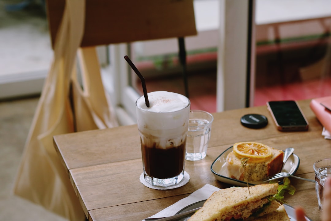 clear drinking glass with latte on brown wooden table