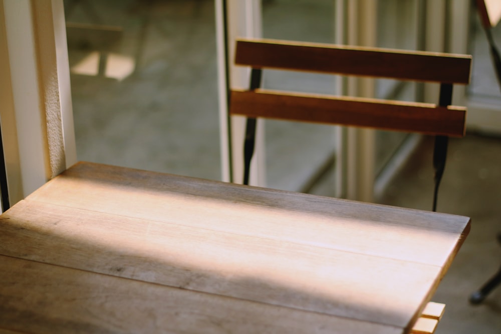 brown desk with chair beside glass panel wall