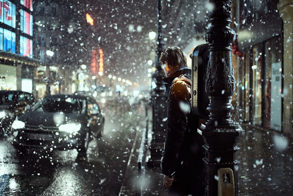 man standing on sidewalk during snowfall