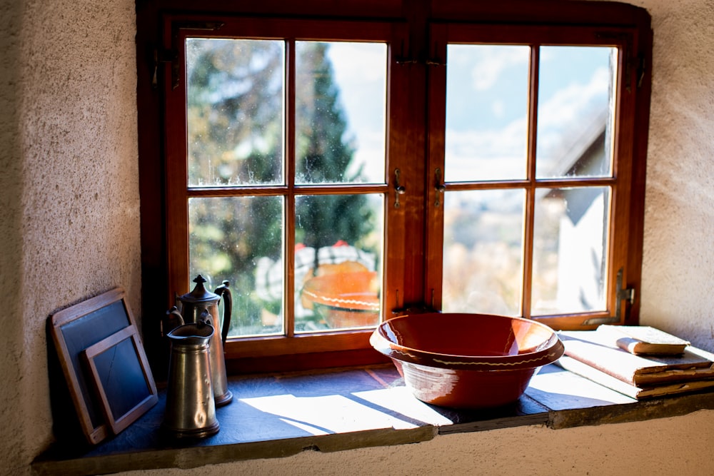 昼間の茶色の木製の窓ガラスの近くの茶色の陶器のボウル