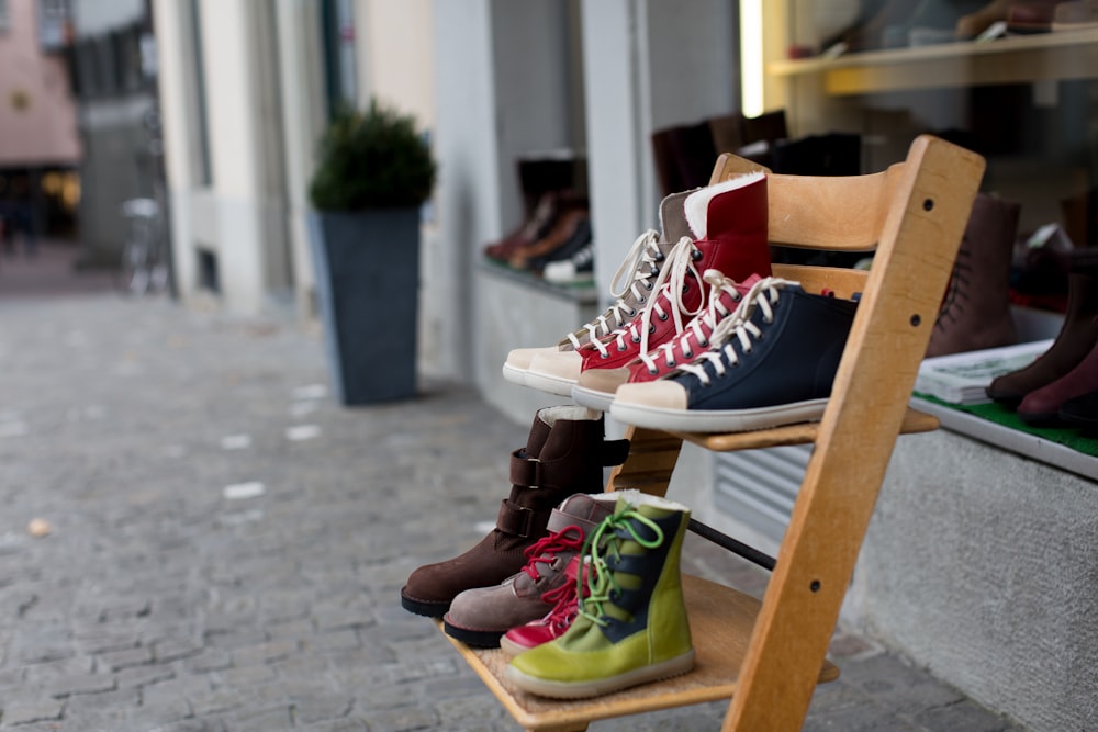 pares de calçados de cores variadas em sapateira marrom de madeira de 2 camadas