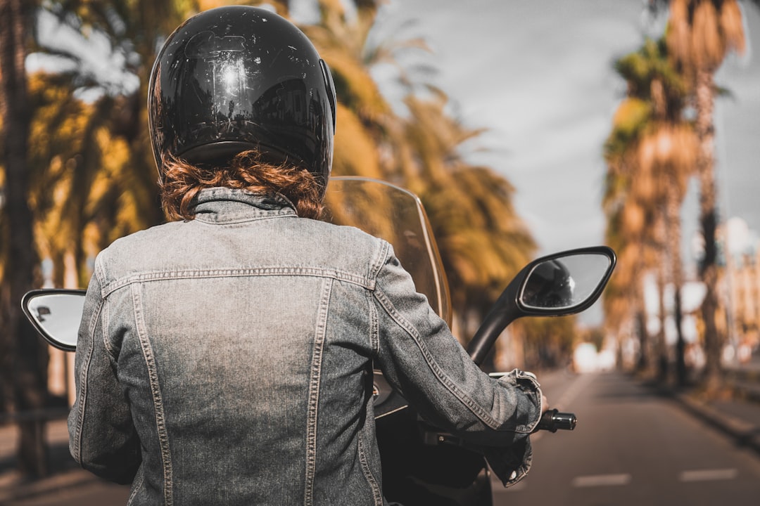 woman wearing grey denim jacket riding motorcycle during daytime