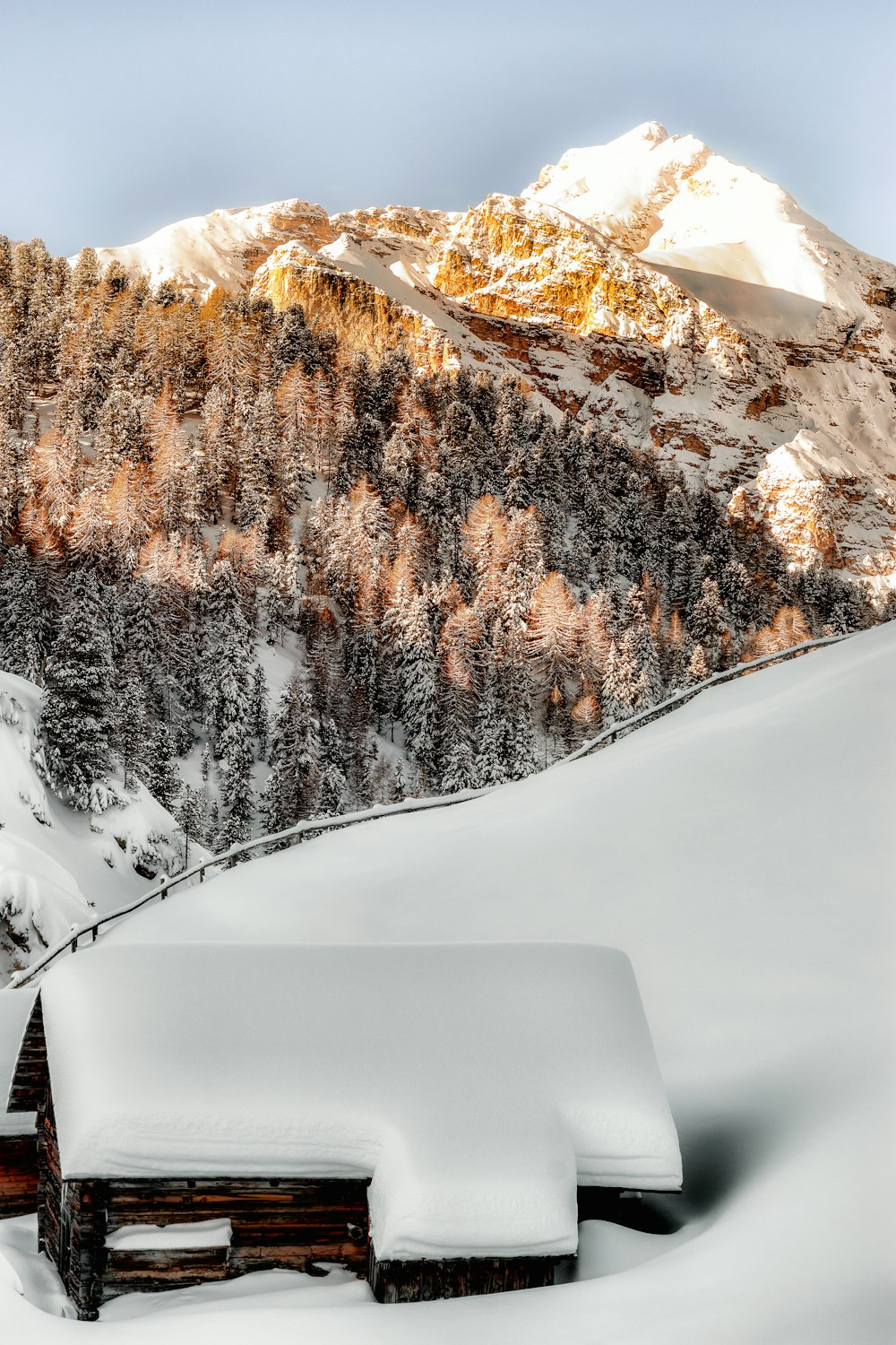山の近くの雪に覆われた茶色の木造家屋の写真