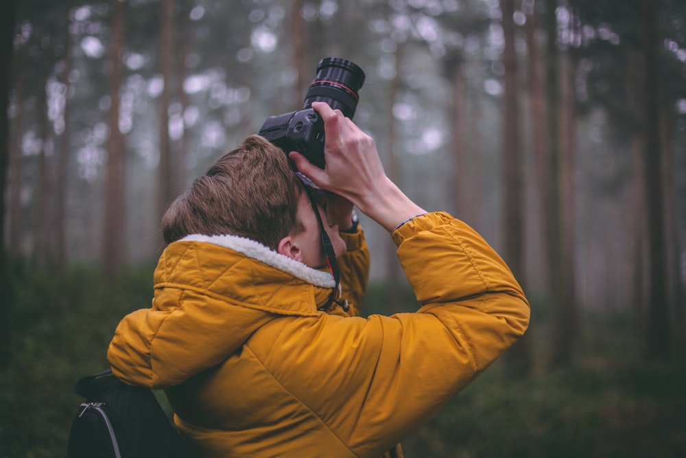fotografía de lente de cambio de inclinación de un hombre sosteniendo una cámara DSLR tomando fotos durante el día