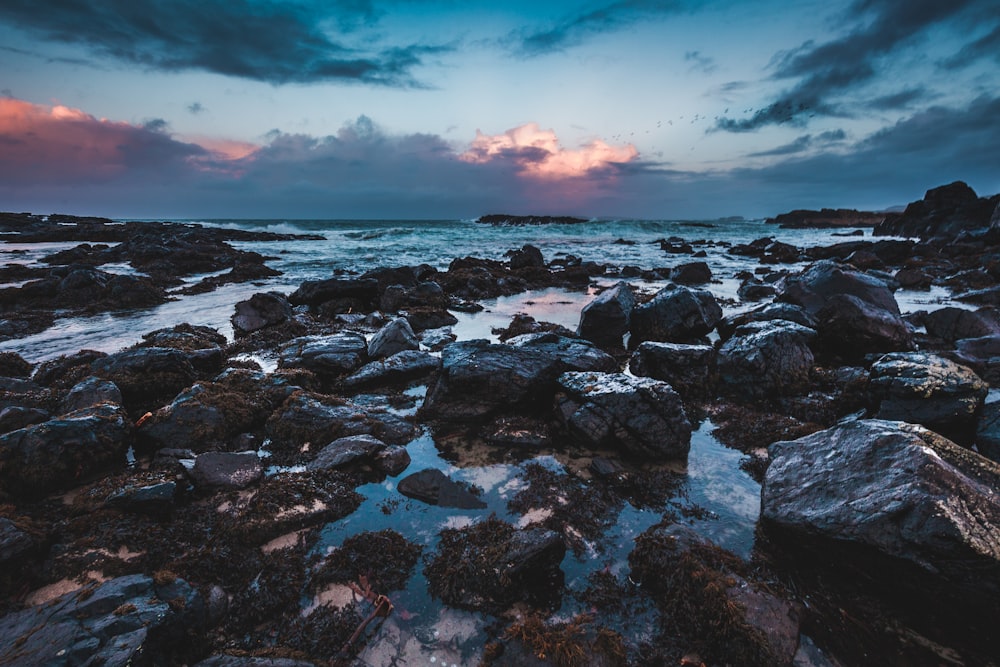 brown rocks near body of water under white and gray sky