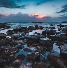 brown rocks near body of water under white and gray sky