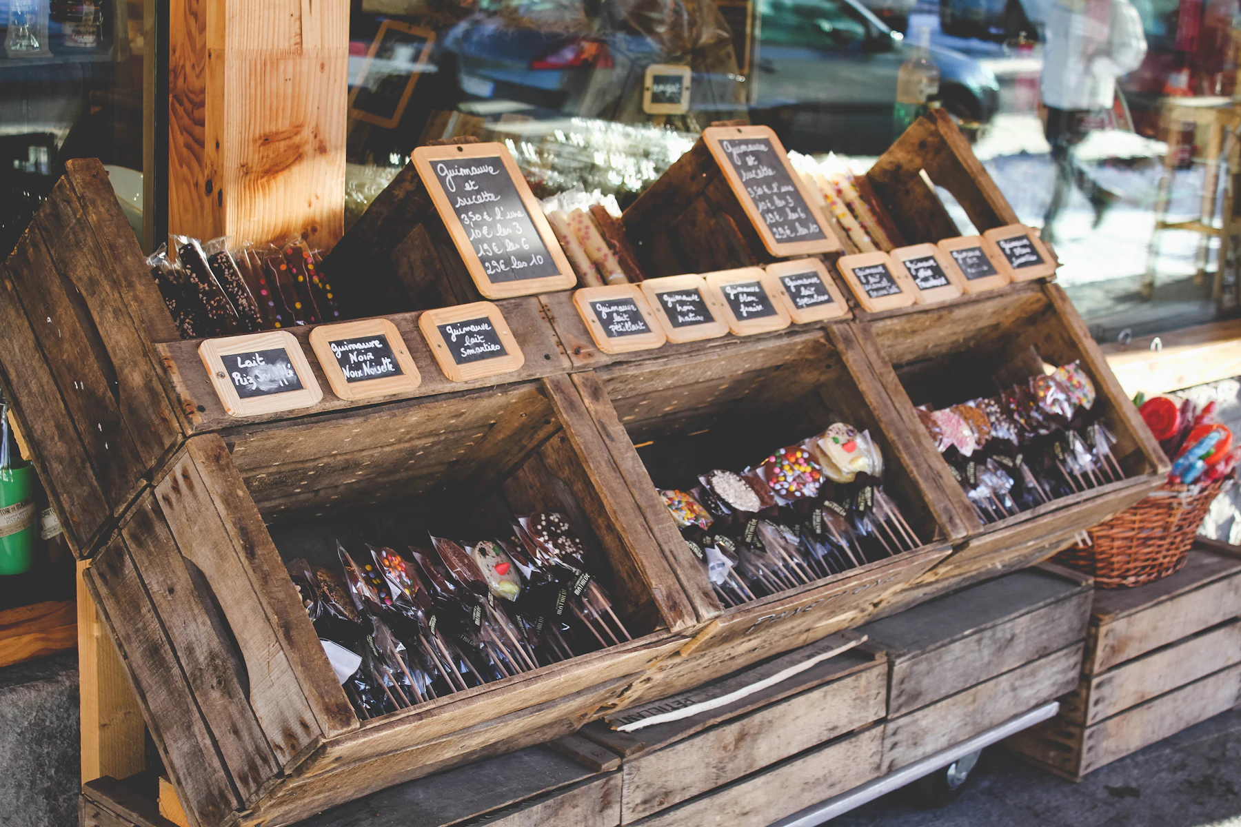 Wooden crates of produce stacked as shelves, small chalkboard labels on each