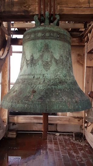 A skilled craftsman tuning a large cast bell inside a historic clock tower.