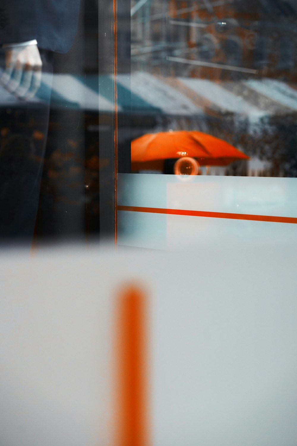 Um guarda-chuva laranja é visto através de uma janela