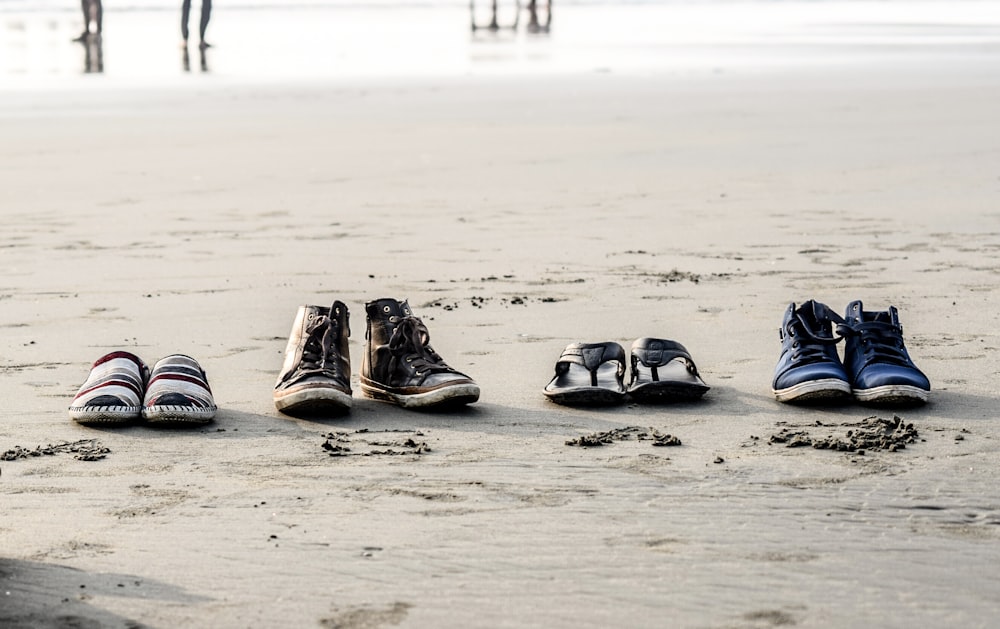 zwei Paar Schuhe und Flip-Flops am Meeresufer in der Nähe von Menschen am Tag