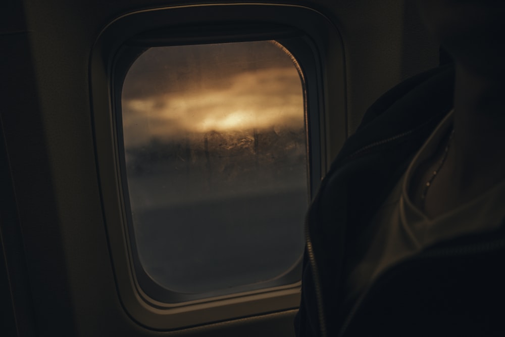silhouette photo of person sitting beside plane's window