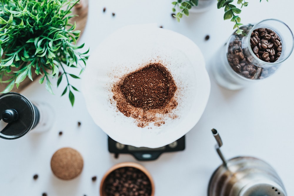 frasco de vidro transparente com grãos de café na mesa branca